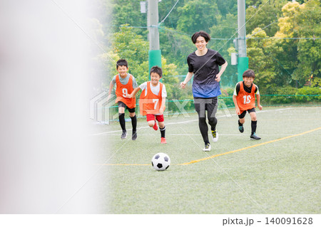 コーチと一緒にボールを追いかけるサッカー少年たち コーチと一緒にボールを追いかけるサッカー少年たち 140091628