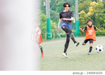 コーチと一緒にボールを追いかけるサッカー少年たち コーチと一緒にボールを追いかけるサッカー少年たち 140091630