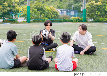 フットサルコートで作戦を説明する男性コーチと少年たち フットサルコートで作戦を説明する男性コーチと少年たち 140091706