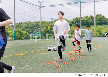 フットサルトレーニングでハードル練習を行う男性コーチと少年たち フットサルトレーニングでハードル練習を行う男性コーチと少年たち 140091721