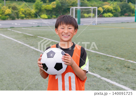 サッカーボールを持って笑顔を見せる少年選手 サッカーボールを持って笑顔を見せる少年選手 140091725