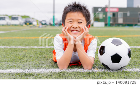 サッカーボールと一緒に笑顔を見せる少年選手 140091729