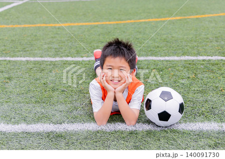 サッカーボールと一緒に笑顔を見せる少年選手 サッカーボールと一緒に笑顔を見せる少年選手 140091730