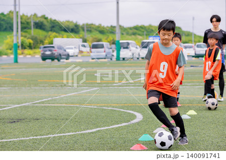 フットサル練習でドリブル指導を行う男性コーチと少年たち 140091741