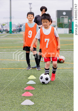 フットサル練習でドリブル指導を行う男性コーチと少年たち 140091747