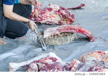 Butcher chopping raw meat with a cleaver on a wooden cutting board Butcher chopping raw meat with a cleaver on a wooden cutting board 140091984