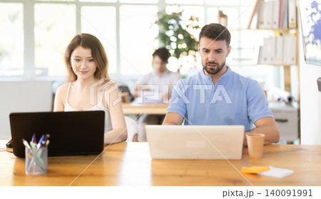 Man and girl staff colleagues working at laptop computer in office room space Man and girl staff colleagues working at laptop computer in office room space 140091991