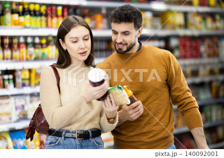 Couple of shoppers are choosing nuts and other food products in food store 140092001
