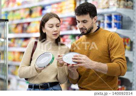 Young couple chooses canned goods in store 140092014