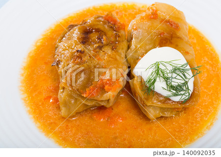 Homemade cabbage rolls in leaves of cabbage at plate with sour cream Homemade cabbage rolls in leaves of cabbage at plate with sour cream 140092035
