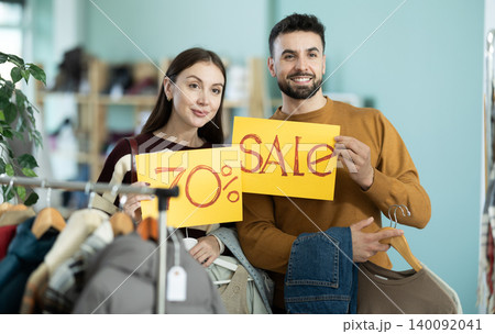 Couple holding posters with discounts and sale in the store 140092041