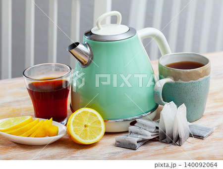Electric kettle and cup of tea on table 140092064