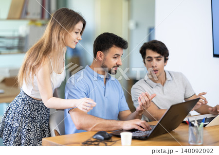 Colleagues discussing project on laptop of man Colleagues discussing project on laptop of man 140092092