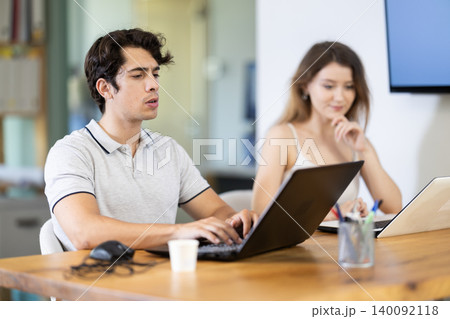 Man and girl staff colleagues working at laptop computer in office room space 140092118