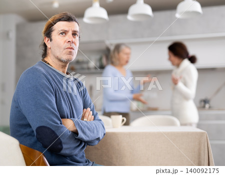 Man was sad because women were arguing in his presence in kitchen Man was sad because women were arguing in his presence in kitchen 140092175