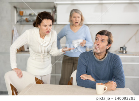 Elderly mother and woman during family quarrel accuse adult man 140092283
