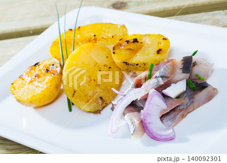 Fried potatoes with slices of mild-cured herring and onions served on plate Fried potatoes with slices of mild-cured herring and onions served on plate 140092301