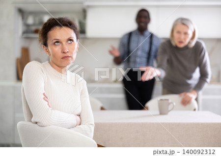 Woman not talking after disagreement with husband and mother standing behind 140092312