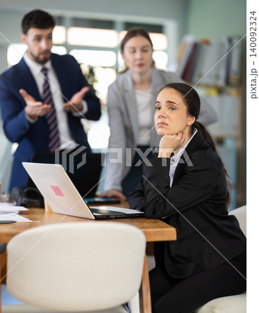 Group of colleagues scolding sad woman in office Group of colleagues scolding sad woman in office 140092324