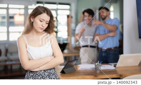 Angry colleagues scolding sad girl during stressful workday in office Angry colleagues scolding sad girl during stressful workday in office 140092343