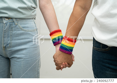 Asian LGBT couple woman holding hand wearing rainbow wristband. Asian LGBT couple woman holding hand wearing rainbow wristband. 140092777