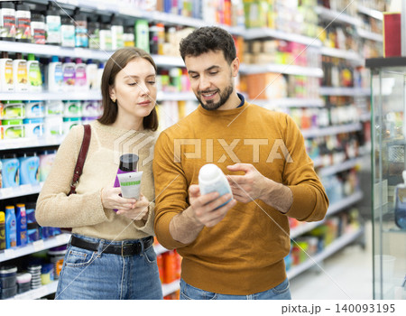 Couple spends time in store, looking for goods and select care product Couple spends time in store, looking for goods and select care product 140093195