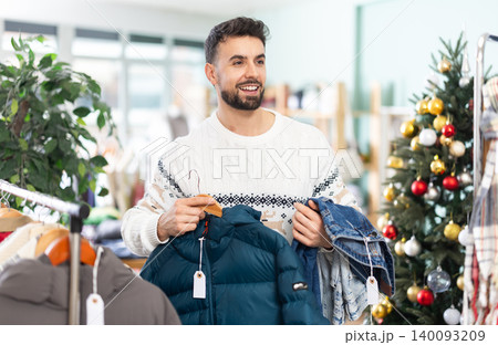 Young man chooses jacket and jeans in store Young man chooses jacket and jeans in store 140093209