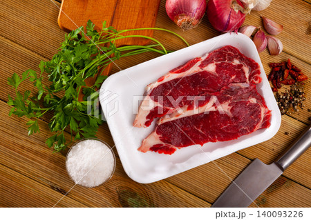 Preparation of raw beef fillet with parsley and garlic on wooden board 140093226