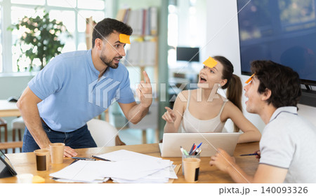 Men and girl with yellow pieces of paper on their foreheads are playing guessing game who am I. 140093326