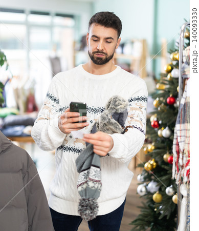 Young man scans qr code of hat in store Young man scans qr code of hat in store 140093330