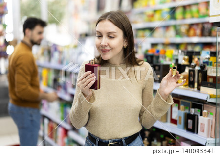 Female buyer choosing bottle of perfume in perfume shop Female buyer choosing bottle of perfume in perfume shop 140093341
