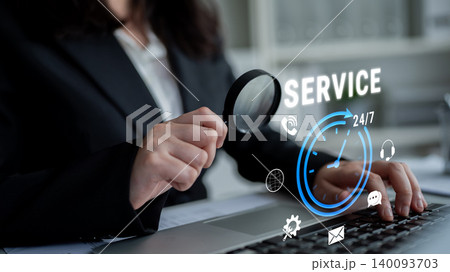 Business professional examining digital service icons on laptop screen with magnifying glass and focus on customer assistance and support Fluxor 140093703