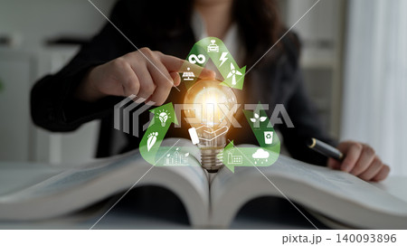 Spark of Innovation: A Business Person Holding a Light Bulb Over an Open Book with Eco-Friendly Icons Representing Sustainability and Energy Solutions Quark Spark of Innovation: A Business Person Holding a Light Bulb Over an Open Book with Eco-Friendly Icons Representing Sustainability and Energy Solutions Quark 140093896