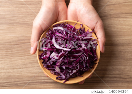 Sliced red cabbage in a bowl with hand on wooden background, Food ingredient, Table top view Sliced red cabbage in a bowl with hand on wooden background, Food ingredient, Table top view 140094394