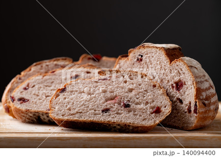 Sliced cranberry sourdough bread on cutting wooden board with black background Sliced cranberry sourdough bread on cutting wooden board with black background 140094400