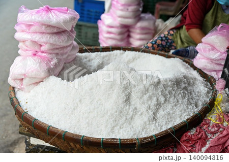 White raw sea salt crystals piled high in basket and packed in pink plastic bags for sale at traditional Asian street market place in Vietnam White raw sea salt crystals piled high in basket and packed in pink plastic bags for sale at traditional Asian street market place in Vietnam 140094816