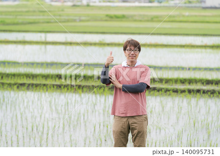 田んぼの畦道に立つ農家の男性 140095731