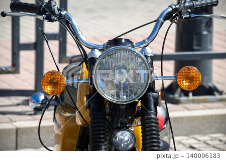 Close-Up Front View Of Vintage Motorcycle Headlight And Turn Signals Parked On Urban Street 140096183