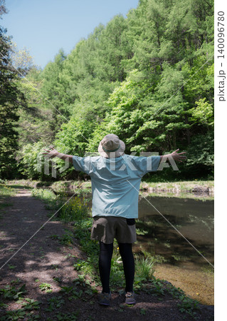 森林浴を楽しみながら深呼吸で両手を広げる女性 アウトドアや夏のキャンプを楽しむ顔無しの後姿イメージ 森林浴を楽しみながら深呼吸で両手を広げる女性 アウトドアや夏のキャンプを楽しむ顔無しの後姿イメージ 140096780
