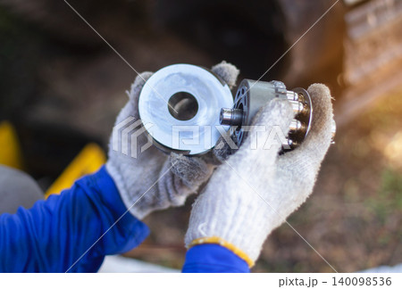 A service technician repairs a damaged hydraulic pump. Professional power hydraulics workshop. Hydraulic motor folding. Disassembly hydraulic piston pump, repair maintenance heavy machinery 140098536