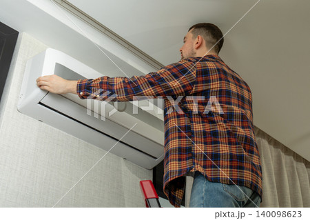 Air conditioner technician installs unit in cozy living space 140098623