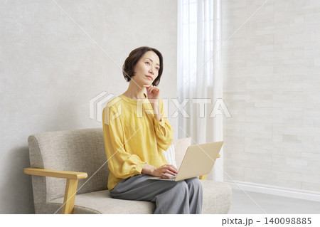 リビングでパソコンを使う女性 考える リビングでパソコンを使う女性 考える 140098885