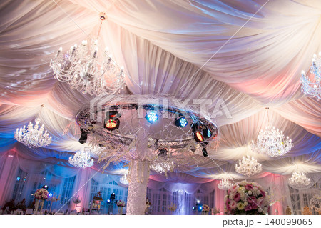Elegant event hall ceiling decorated with crystal chandeliers and white drapery 140099065
