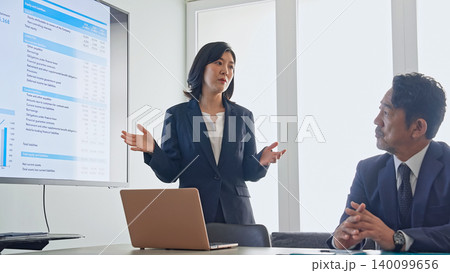 画面を見ながら会話するビジネスパーソンのグループ 140099656