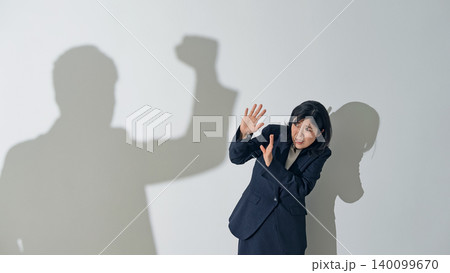 男性のシルエットに叩かれる女性ビジネスパーソン 男性のシルエットに叩かれる女性ビジネスパーソン 140099670