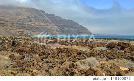 Wide view of Lanzarote desert landscape with volcanic hills and stark island beauty Wide view of Lanzarote desert landscape with volcanic hills and stark island beauty 140100076