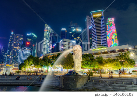 Tourist beside the Merlion statue fountain, iconic symbol of Singapore, overlooking the Marina Bay waterfront in the night 140100108