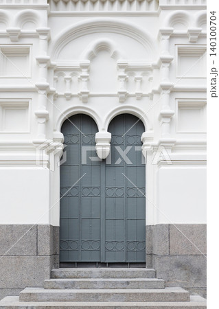 Elegant arched double door set into a white, ornate classical Church facade 140100704
