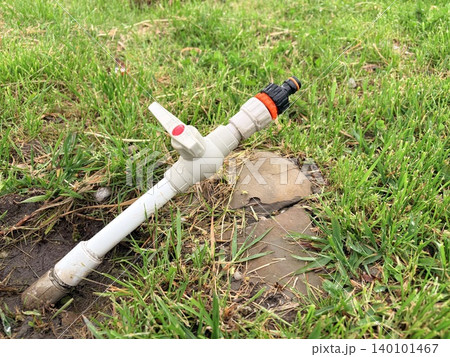 irrigation system for watering the lawn. PVC pipe protruding from the ground in a grassy area. irrigation system for watering the lawn. PVC pipe protruding from the ground in a grassy area. 140101467