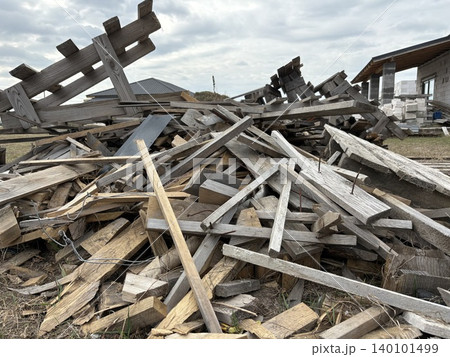a large, disorganized pile of construction waste and discarded wood resting on a grassy field. a large, disorganized pile of construction waste and discarded wood resting on a grassy field. 140101499
